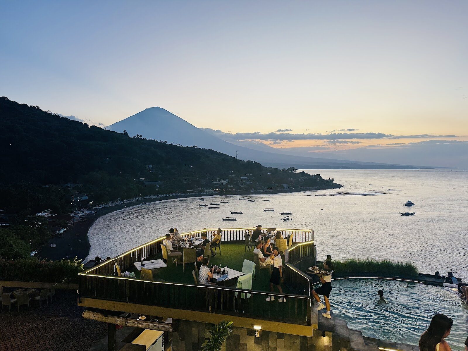 A clifftop viewpoint over the bay at dusk, Agung looming behind the water.