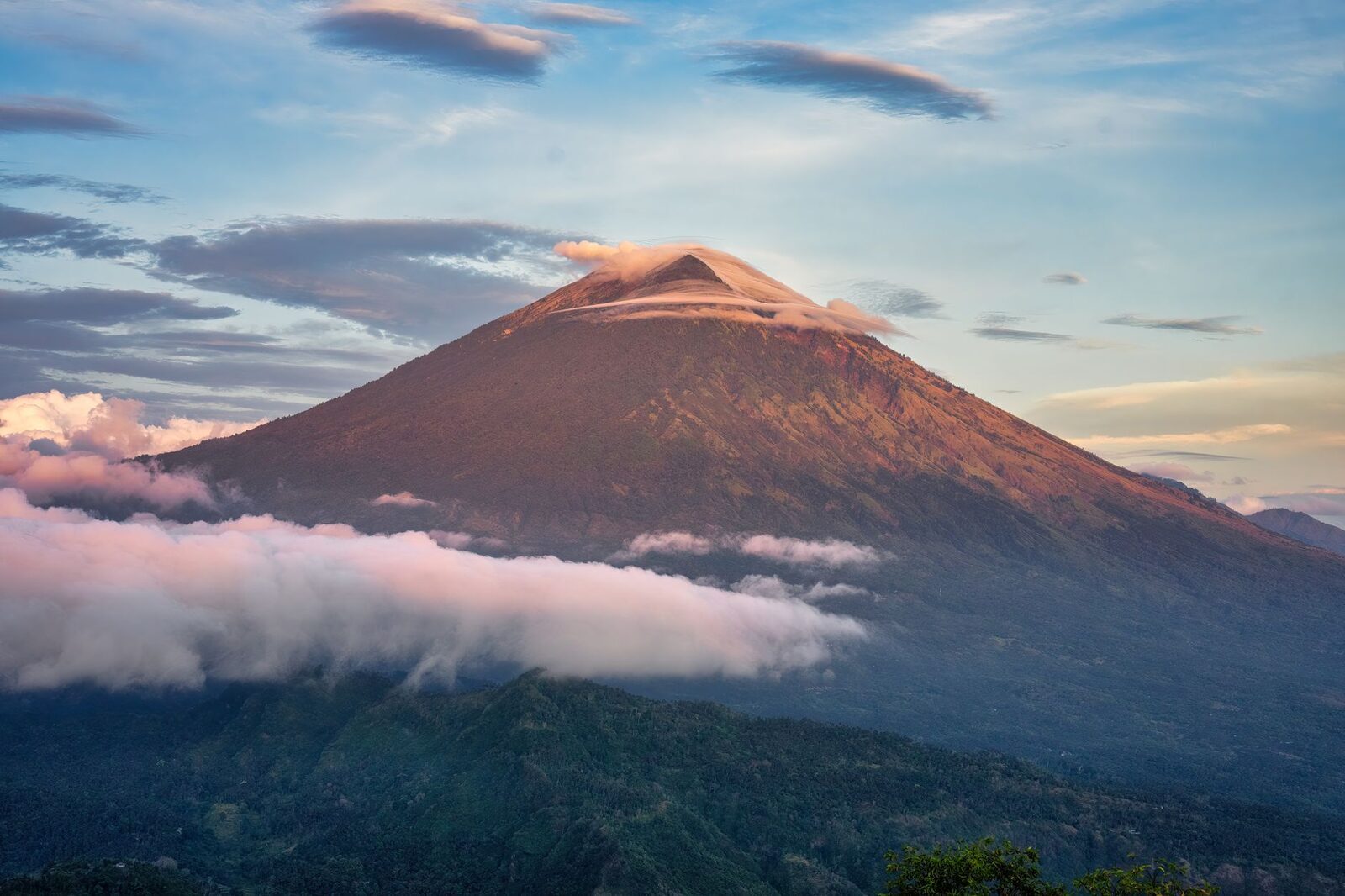 Mount Agung catching pink light at dawn — the volcano that backs this whole coast.