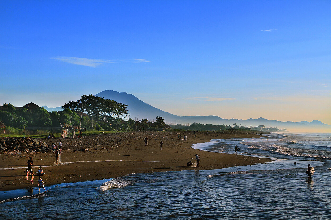 Waders in the shallows on the dark volcanic sand, the hills of the east coast behind.
