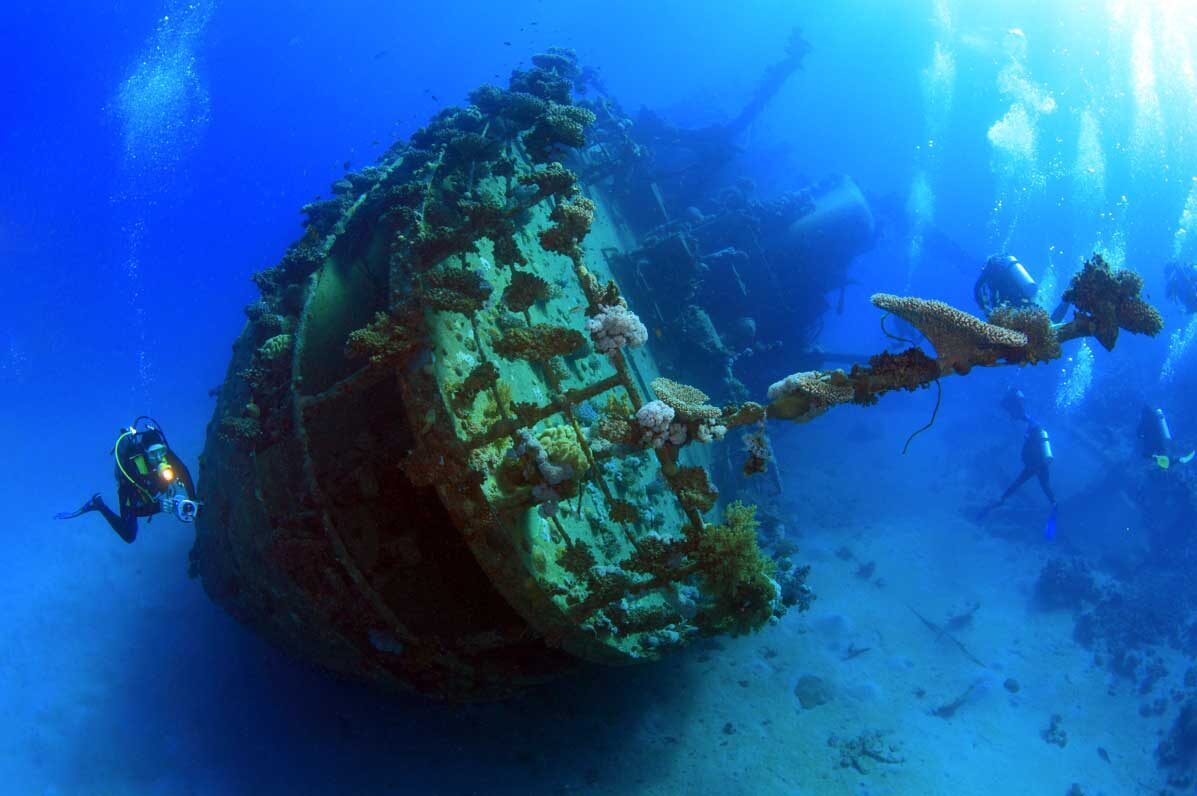 A diver over the Liberty's bow and propeller at Tulamben, the steel thick with soft coral.