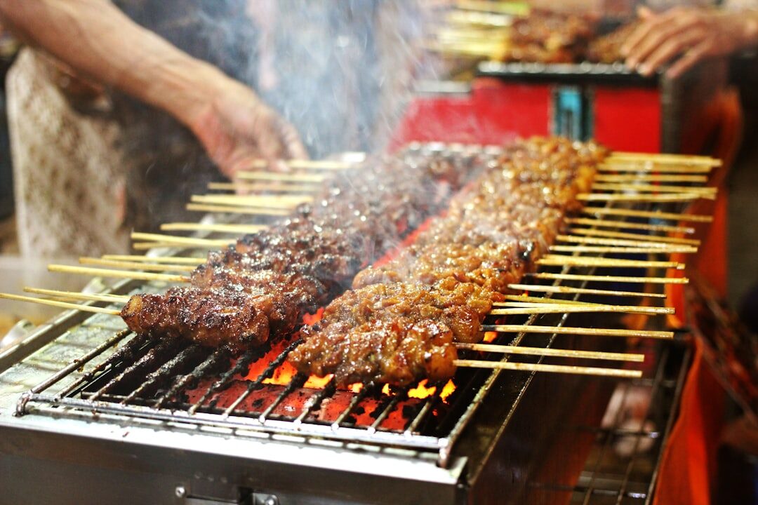 Skewers of satay turning over the coals — cooked-to-order and properly hot is what you want.