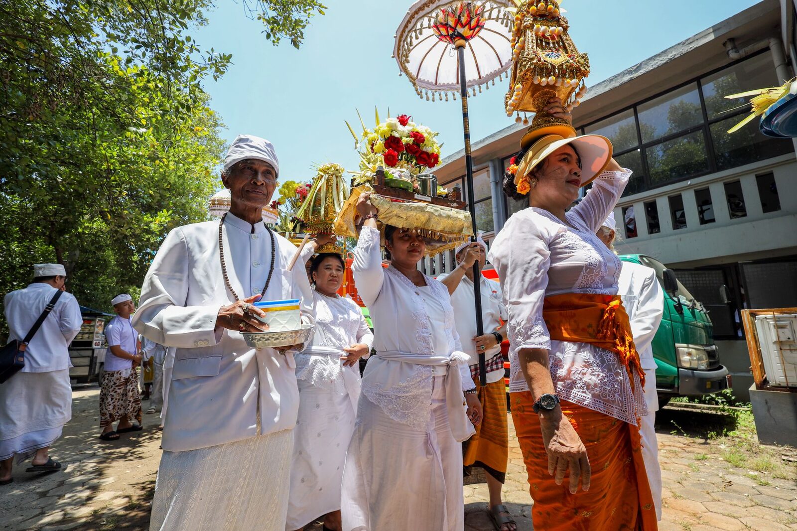 Carrying offerings and a tedung parasol in procession — ask before photographing anyone up close; almost everyone says yes.
