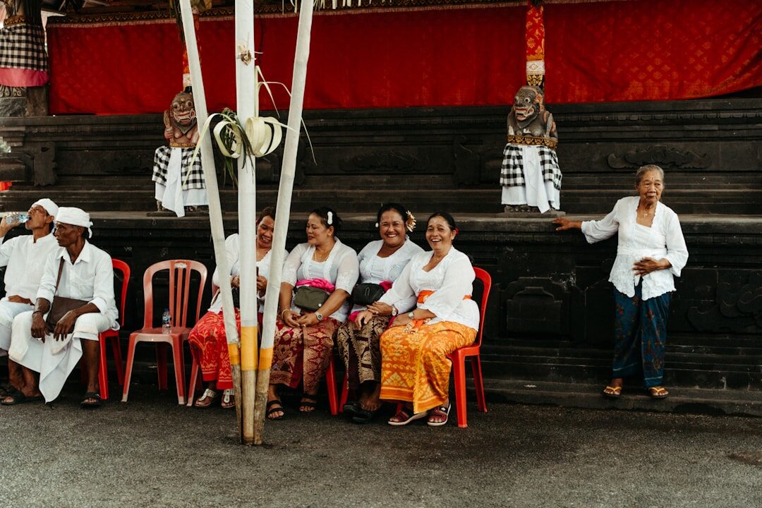 Elders seated in ceremonial dress under the penjor. Never stand higher than the priest; if in doubt, get lower.