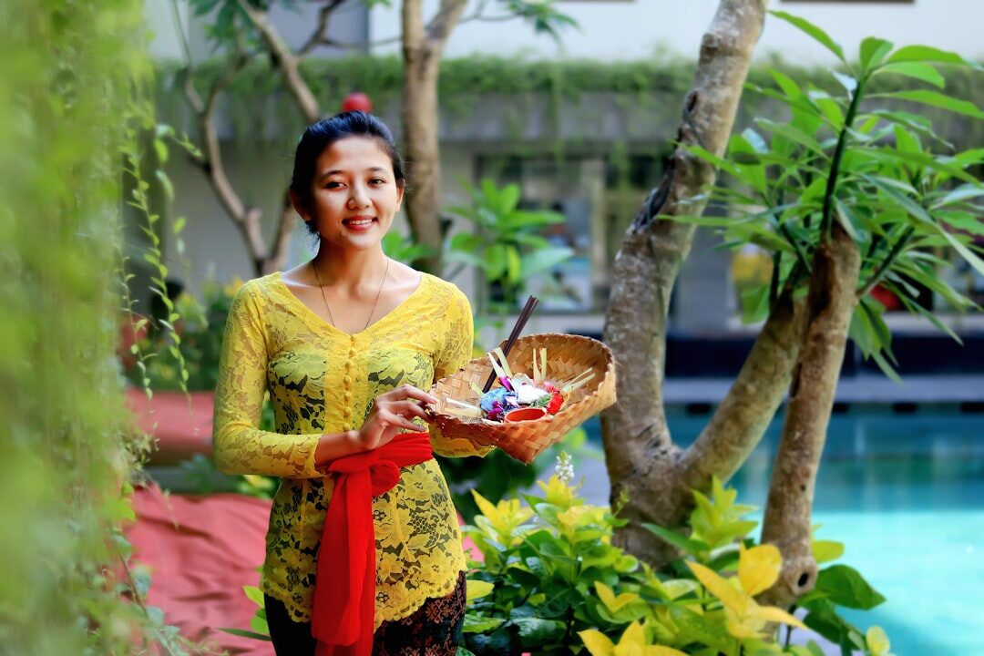 A woman in a yellow kebaya carrying her offering. Beachwear belongs on the beach, and nowhere else.