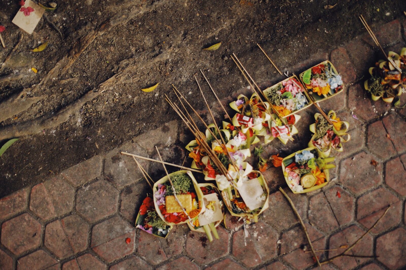 Offerings set right in the middle of the pavement. The courtesy is small but it matters: don't step on them, don't step over them — just walk around.