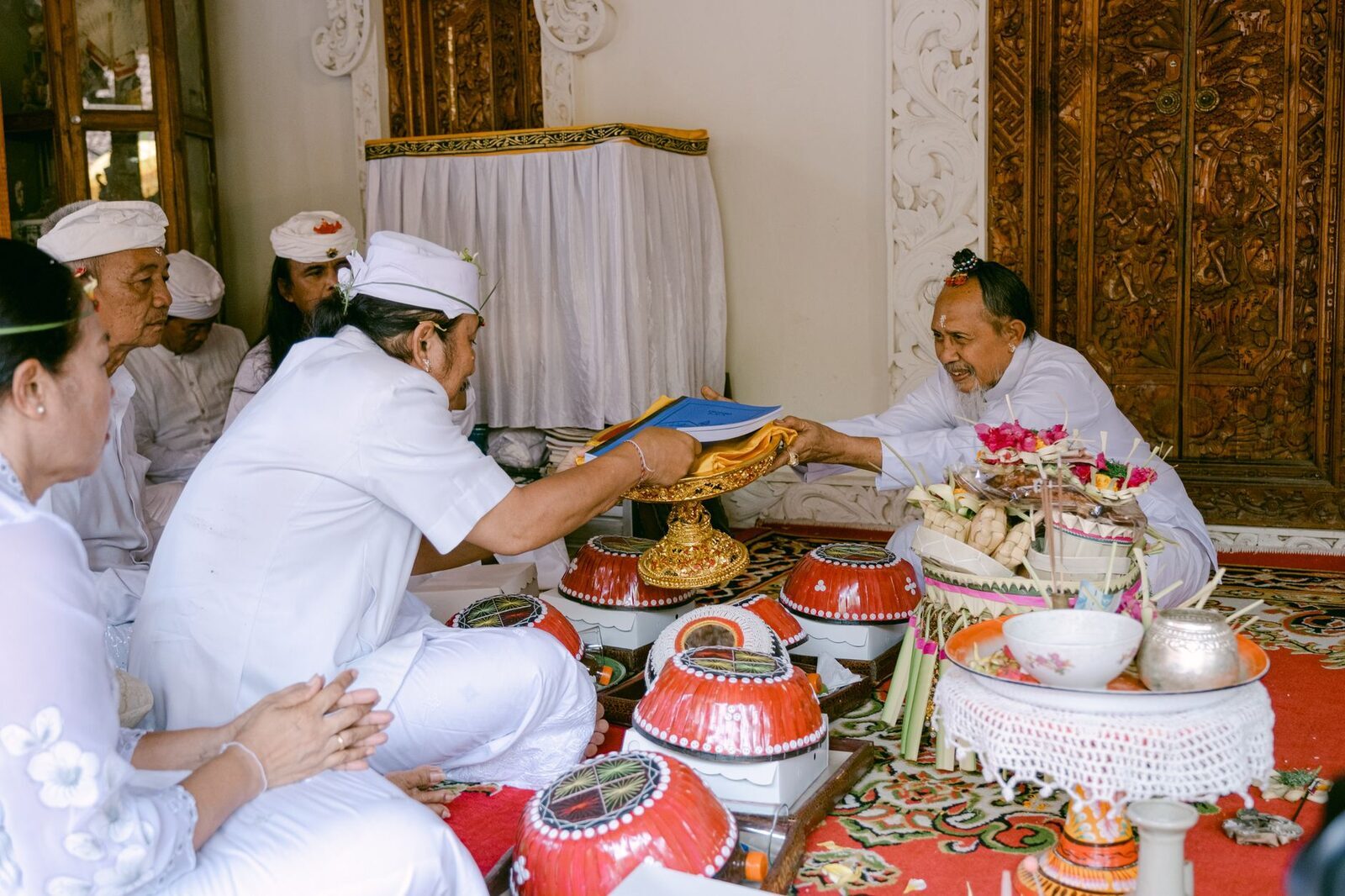 Families in white and gold gathered with their offerings during a temple ceremony.