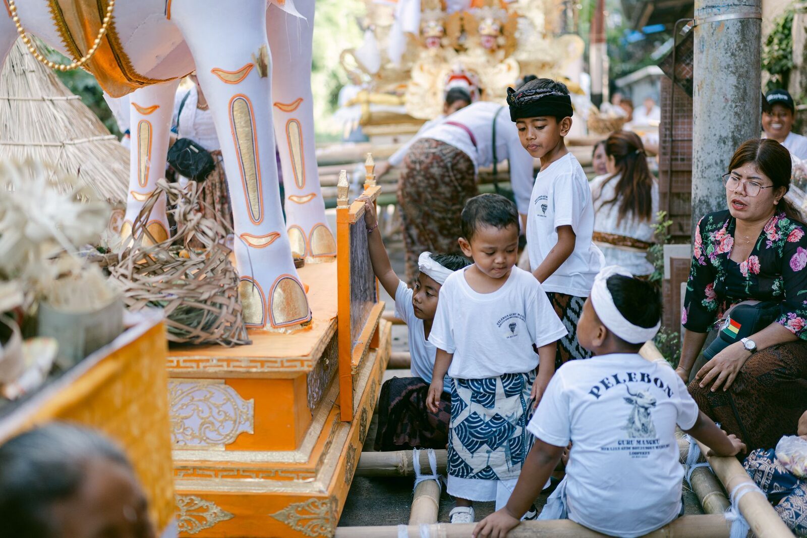 A tall gilded cremation tower borne along by the family, a child riding among the bearers.