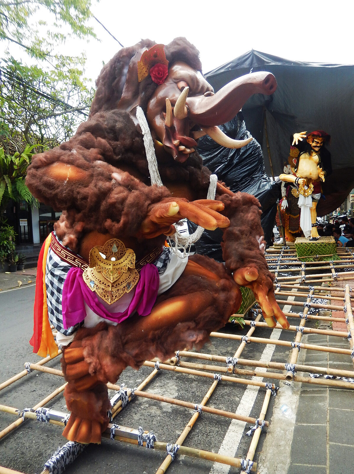 A brown, shaggy demon effigy lashed to its bamboo frame, ready to be paraded and spun at the crossroads.