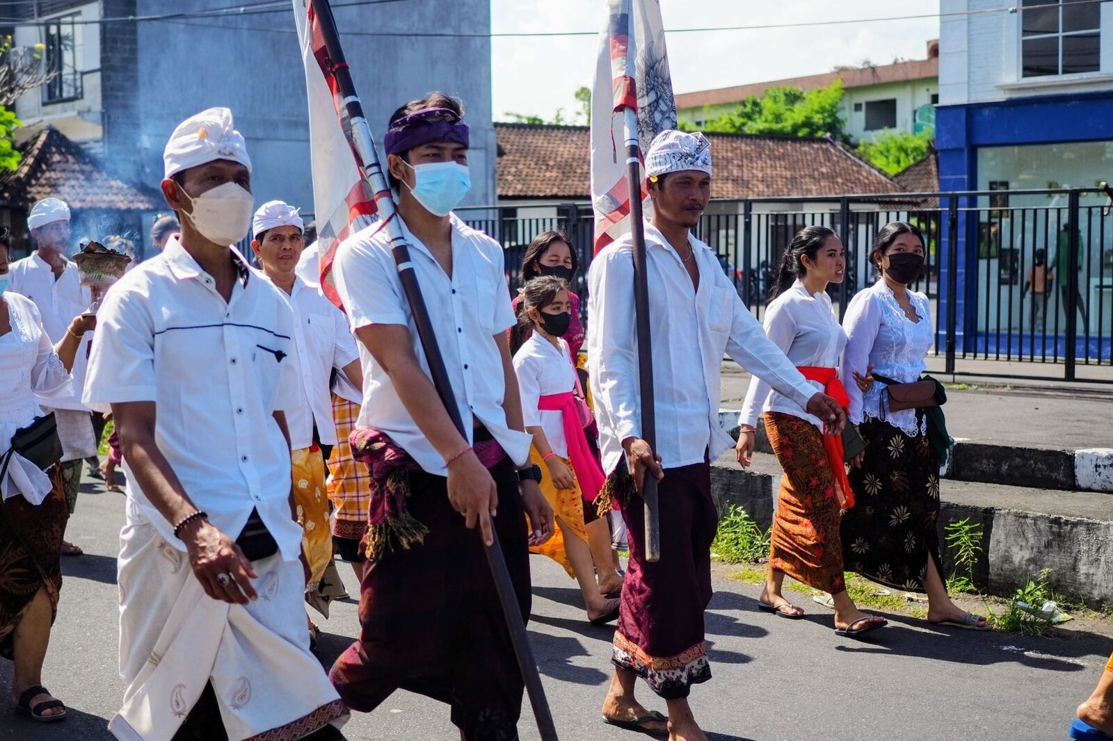 A men's procession in ceremonial white carrying a temple banner.