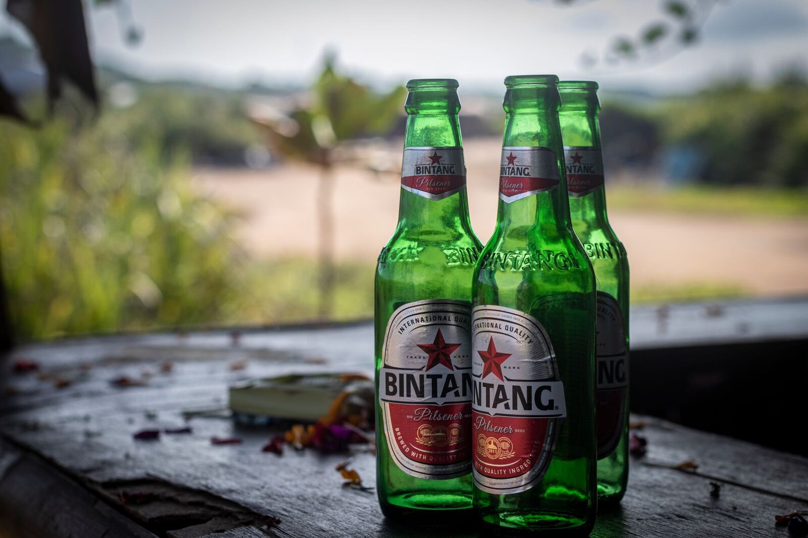 A big cold Bintang on the table by the beach — a few dollars, and the whole trick to keeping the drinks line invisible. The imported cocktails are the quiet budget killer, not the beer.