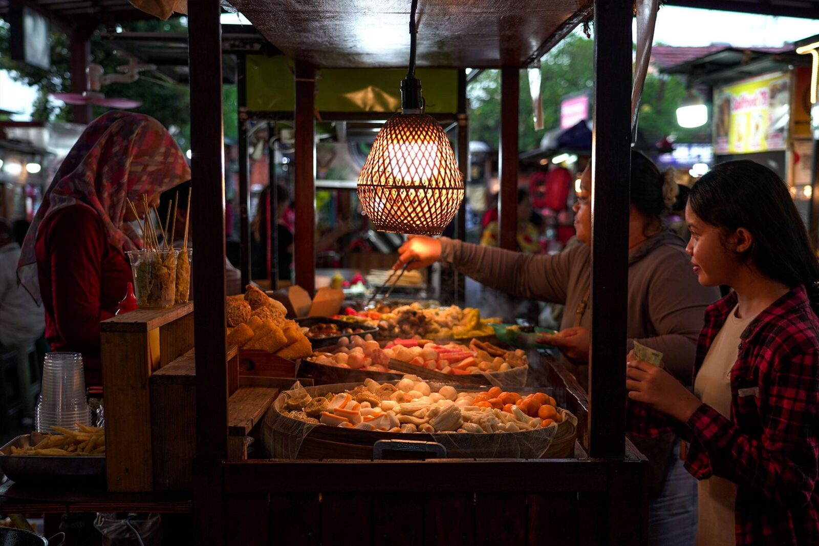 A warung after dark. With no price list, just ask 'how much?' before you order and say it back to confirm — that's where a 30,000-rupiah plate quietly becomes 150,000.