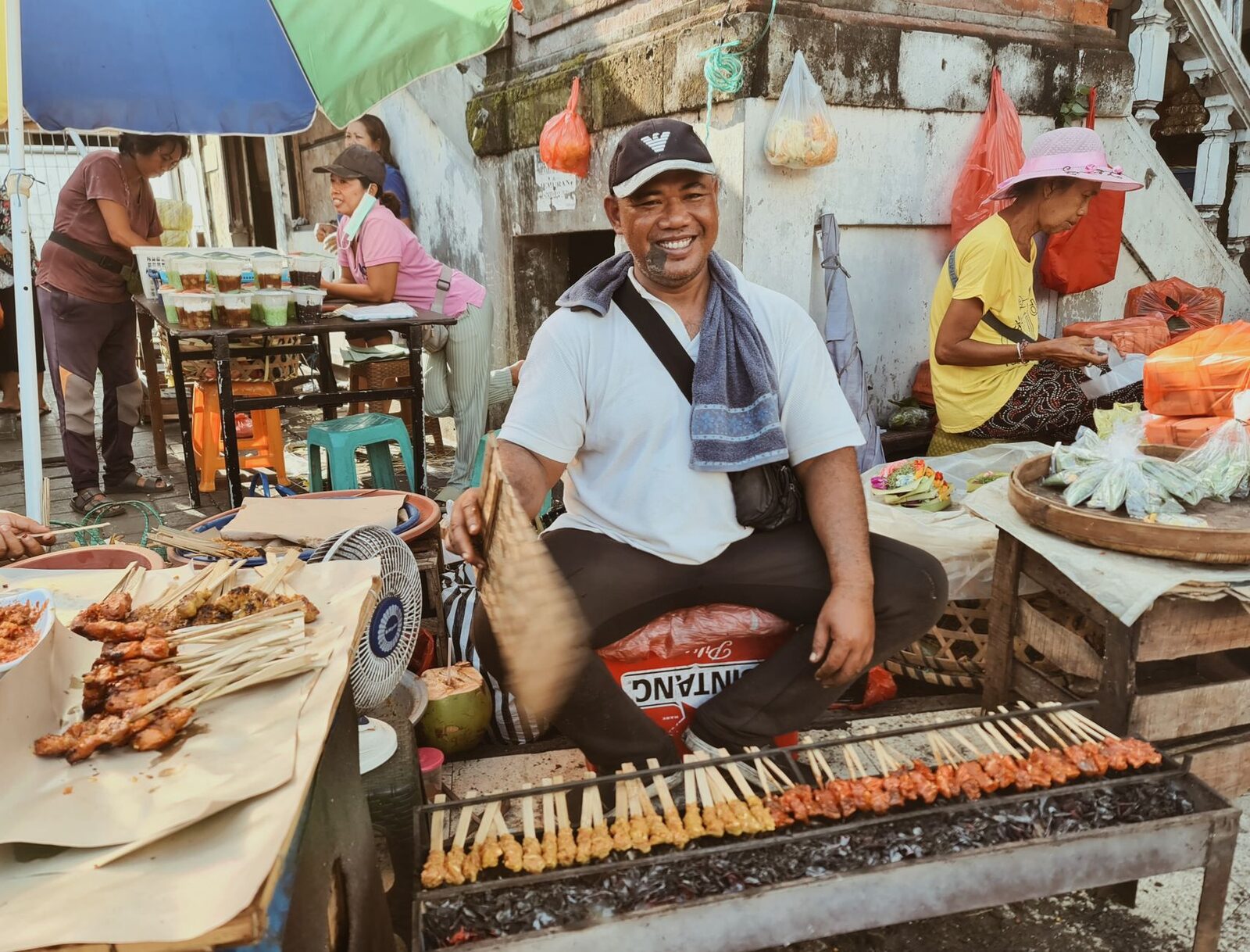 A satay grill going at a street warung. Agree the price before you eat, before the massage, before you commit to the sarong — before, never after. Tap any image for its source and licence.