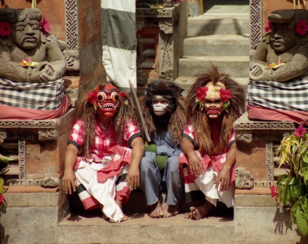 Masked characters of the Barong drama resting on the temple steps.