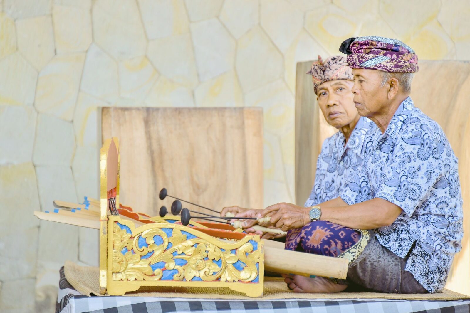 Two players sharing a single bamboo instrument — the interlocking kotekan technique in miniature.