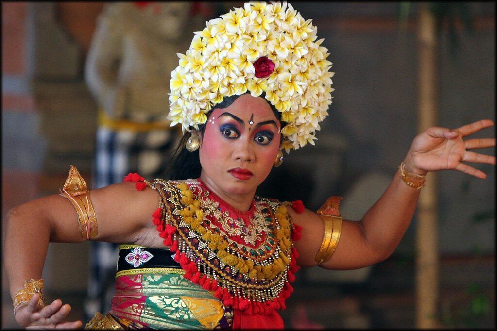 A Legong dancer in a frangipani-laden gilded crown — the darting eyes that carry the dance.