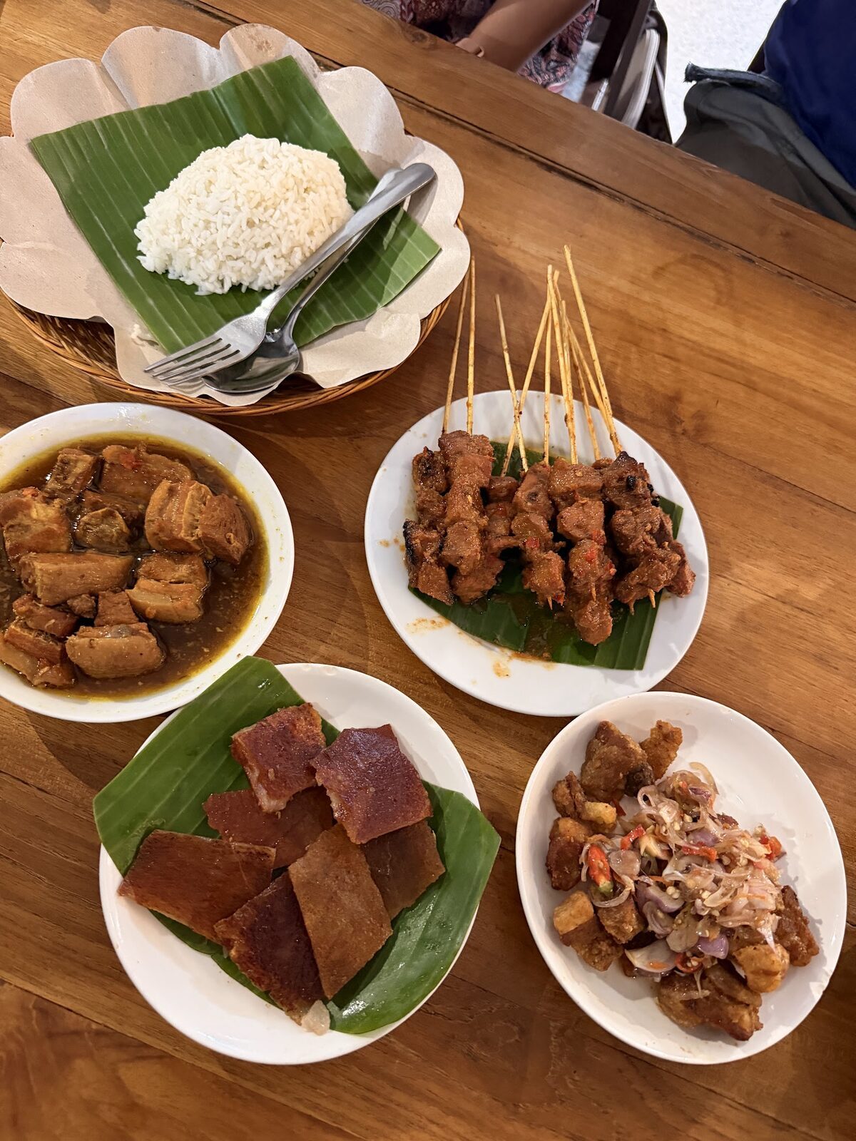 A Balinese spread: rice, satay, lawar and sambals laid out together.