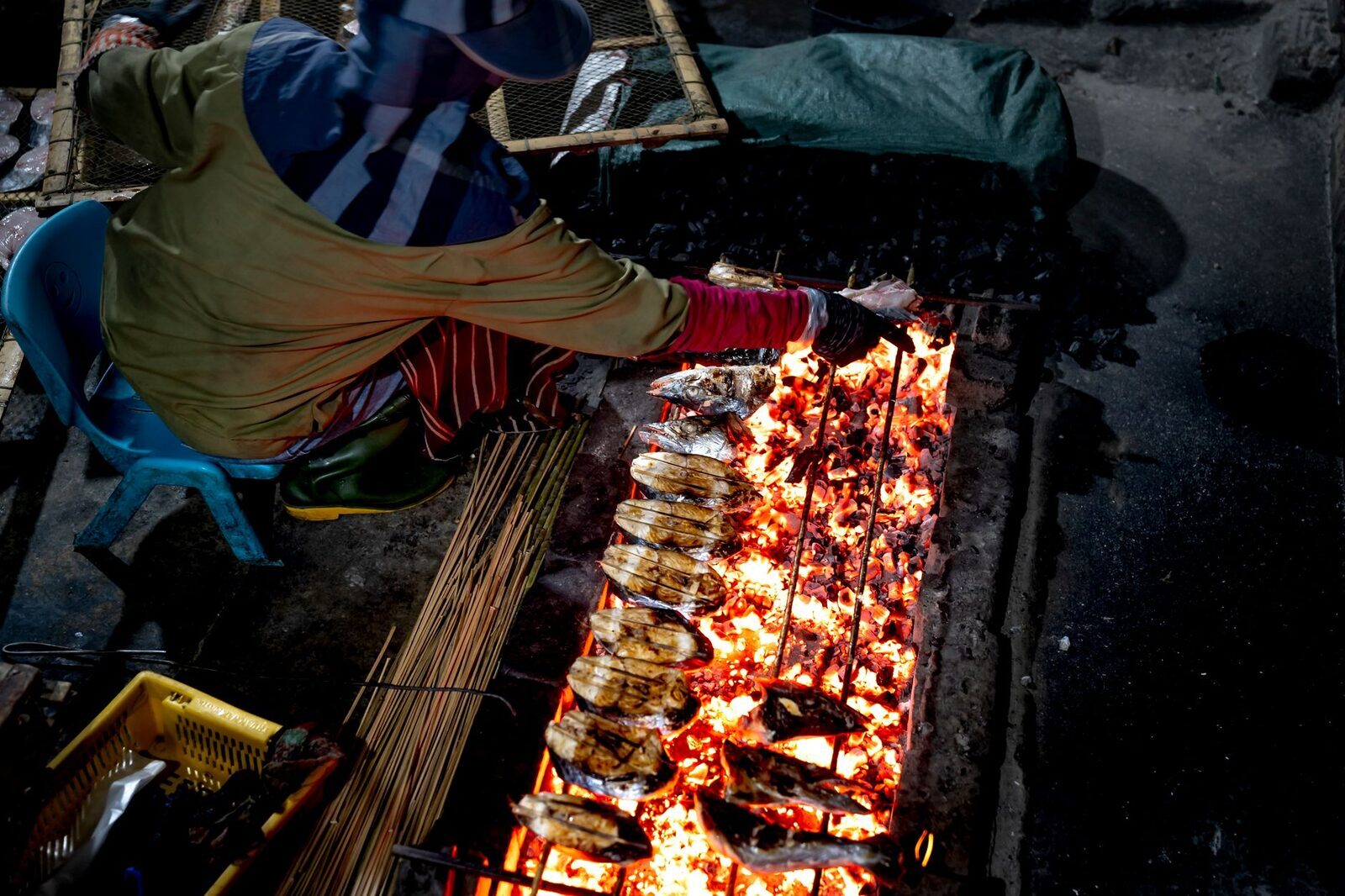 Rows of fish and skewers grilling over open flames.