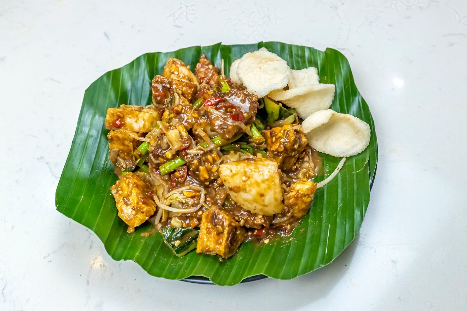 Tempeh and tofu fried in sweet-spicy sambal on a banana leaf — the meat-free staple you'll find everywhere.