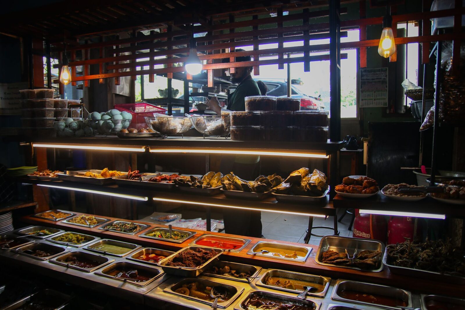 The hot display at a warung — the day's dishes cooked once in the morning and sold till they run out. The high-turnover ones are often the best food on the island.