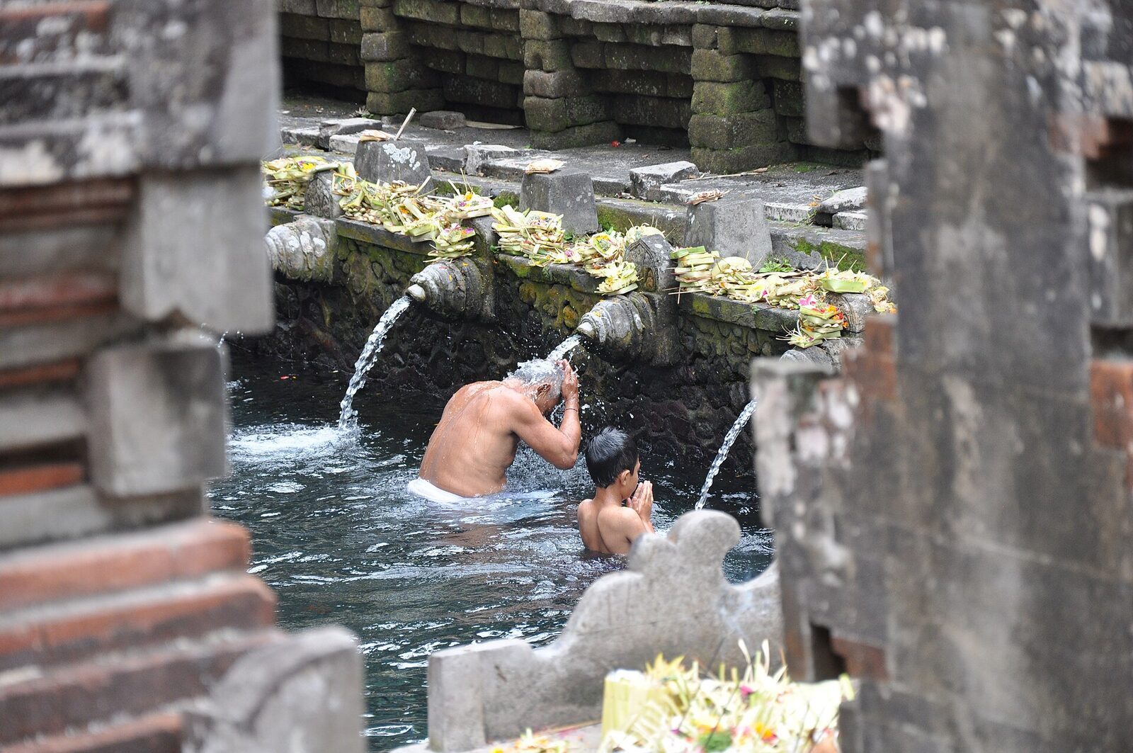Ducking under a single spout at the source, an offering resting on the ledge above.