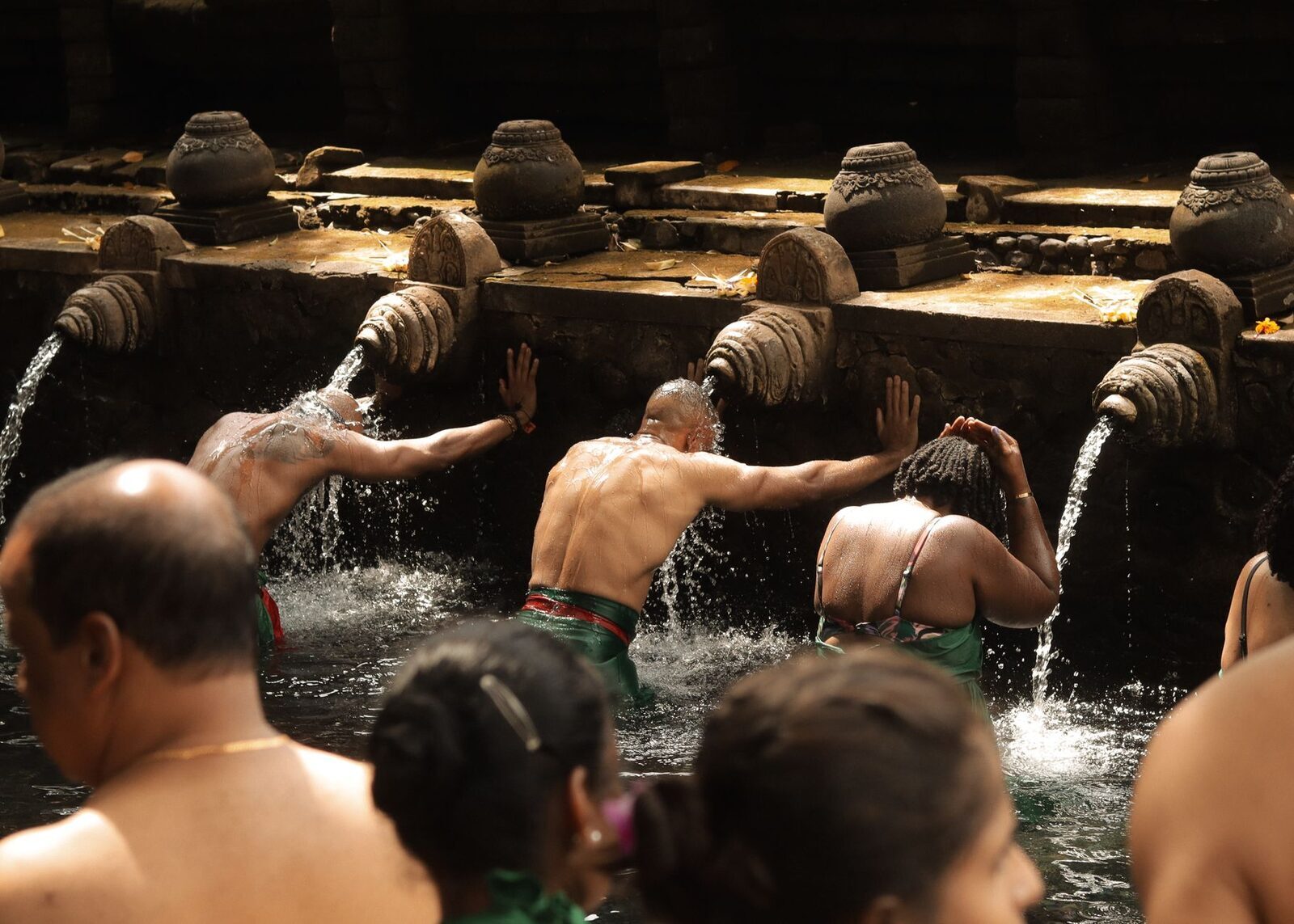 The row of spouts in low golden light, worshippers moving from one to the next.