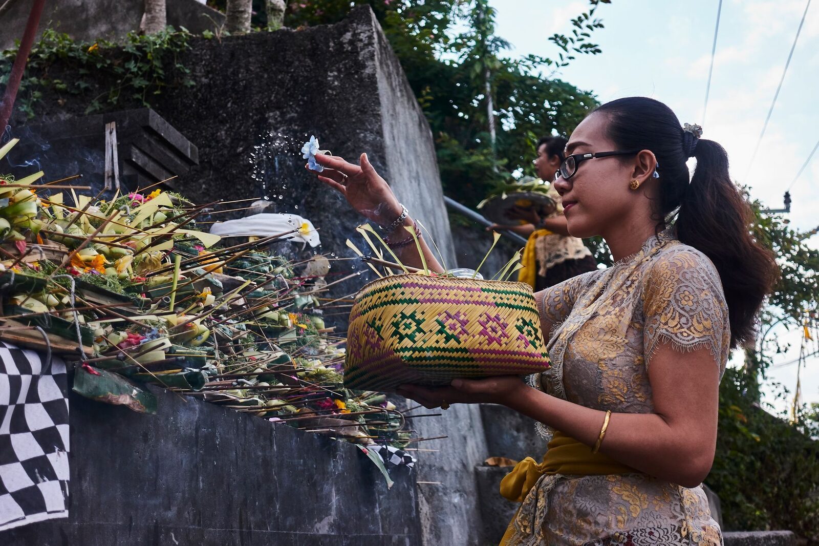 Scattering petals and holy water over an offering: the blessing that turns leaves and flowers into a gift to the unseen.