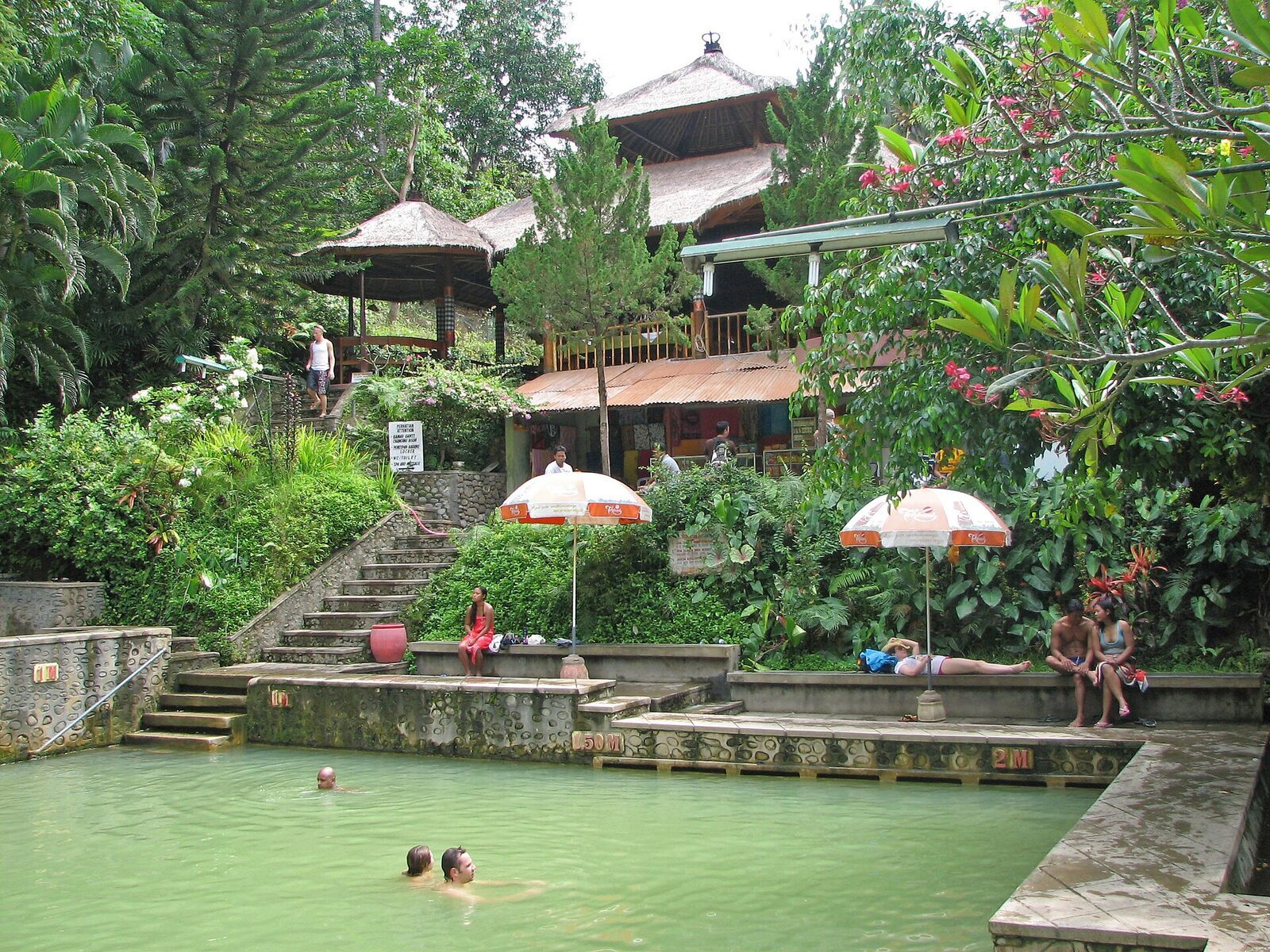Steps, sun umbrellas and bathers in the green sulphur water — busy by midday.
