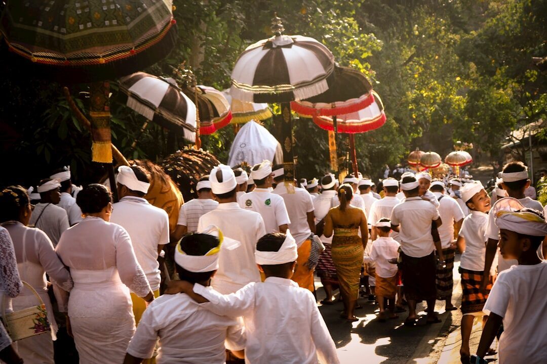 A Balinese procession files into a temple behind a ceremonial umbrella — dress modestly and keep your distance on days like this.