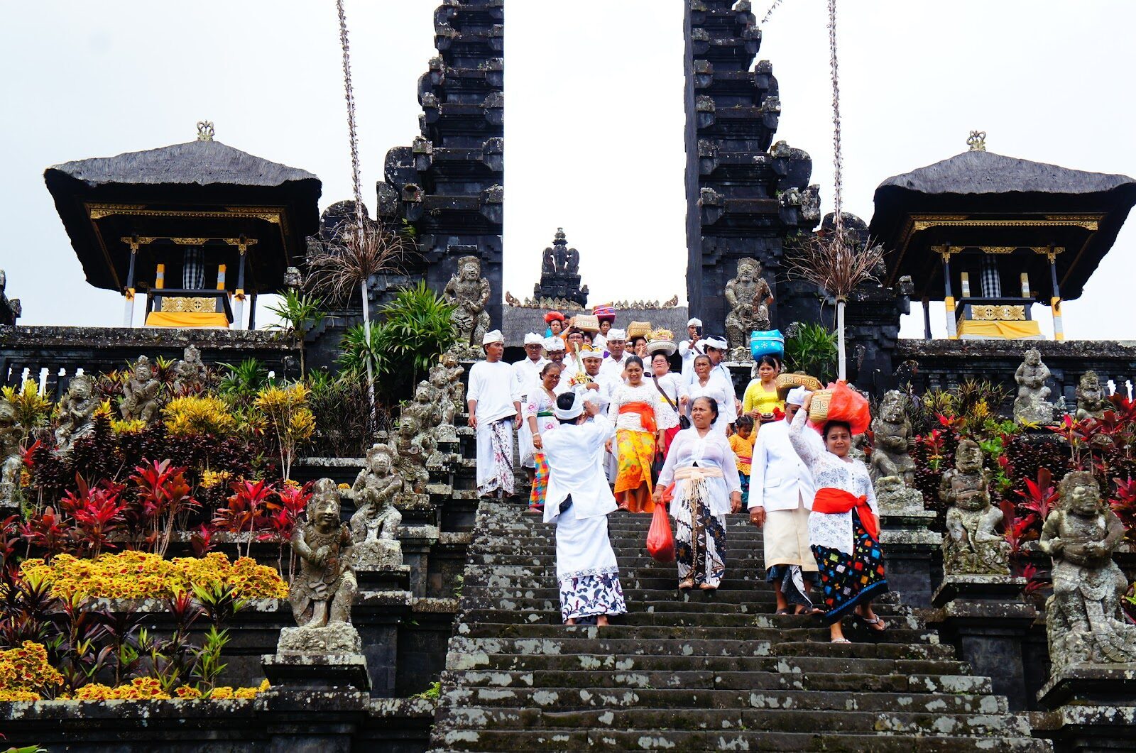 Worshippers in ceremonial white climb Besakih's great stairway on a temple-anniversary day — the whole complex comes alive.