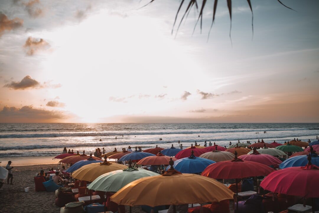 A sea of beach umbrellas at golden hour on a crowded stretch of sand.
