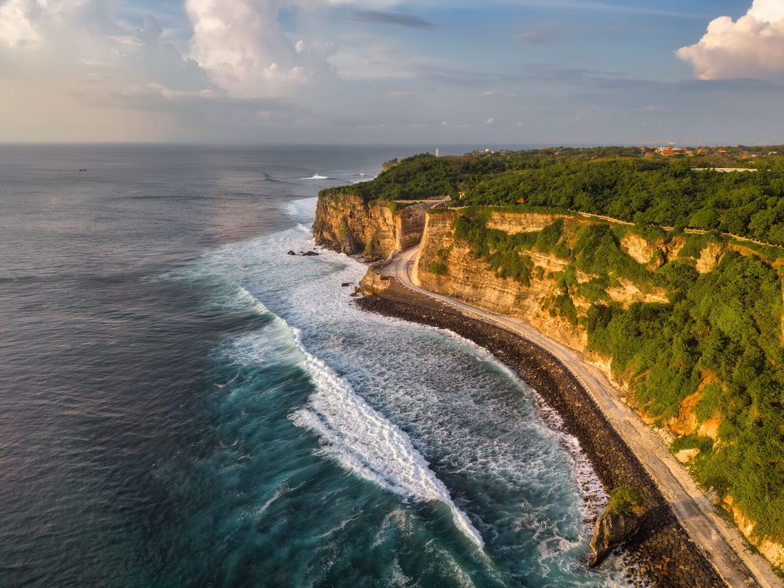 Golden light on the Bukit cliffs and a rolling swell — classic dry-season conditions.