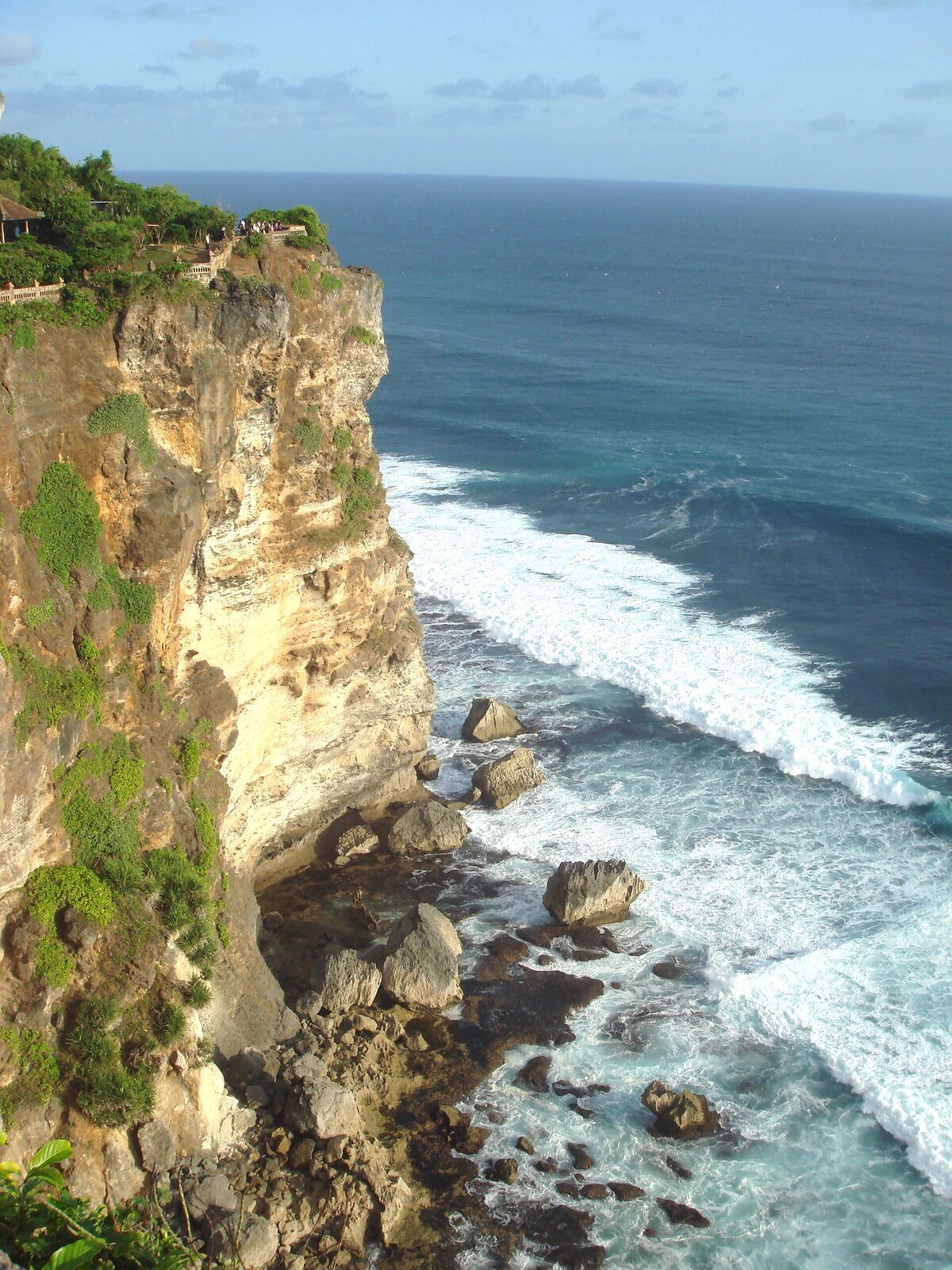 Scrub-topped cliff and surf on the exposed southern shore.