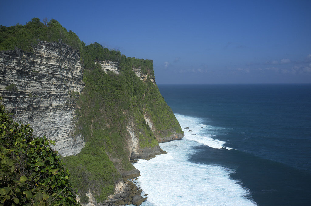 The Bukit's white limestone cliffs dropping straight to a turquoise reef sea — a drier, harder-edged island than the rice-terrace Bali of the postcards.