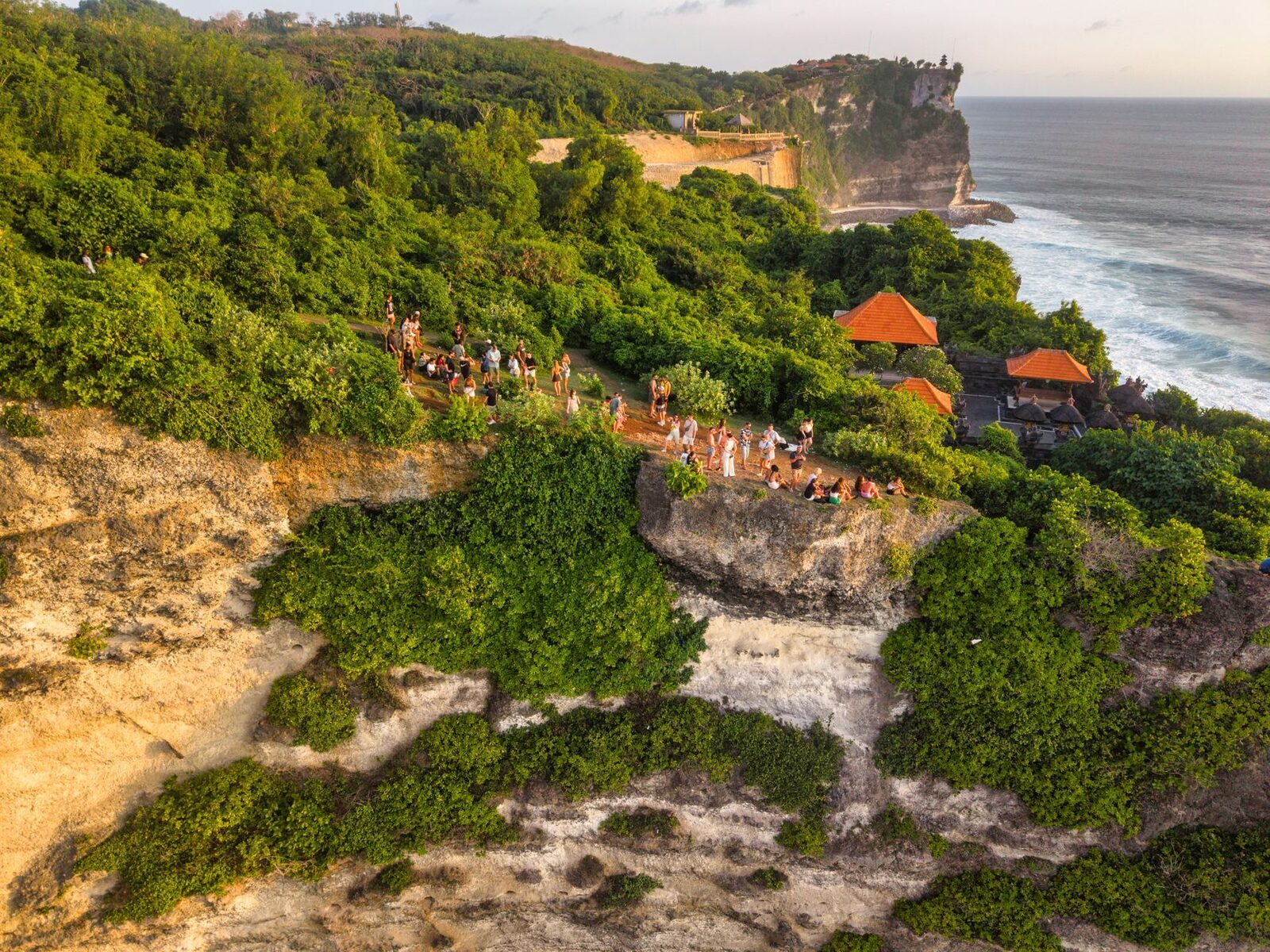 An aerial look at the temple complex strung along the cliff edge, the crowds gathering for sunset.