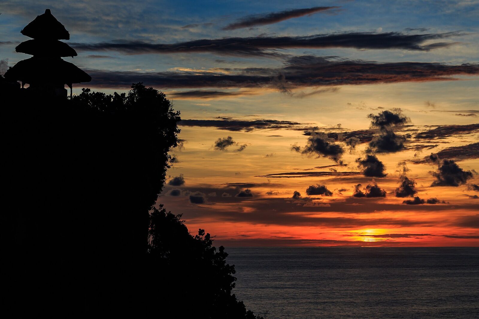 Dusk over the temple silhouettes — the hour when the Kecak performance begins.