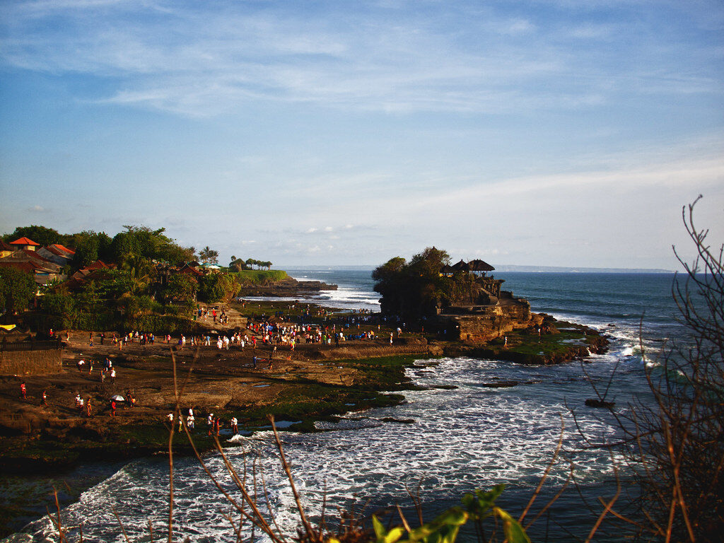The wide view of the shoreline complex at dusk, crowds spread across the rocks.
