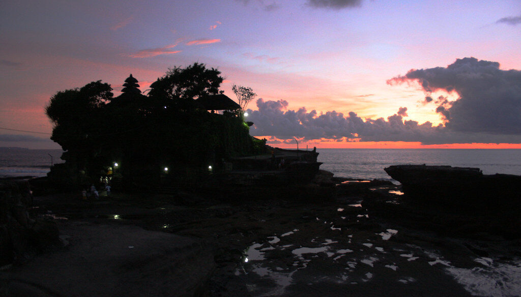 A pink-sky silhouette of the temple across the tidal flats.