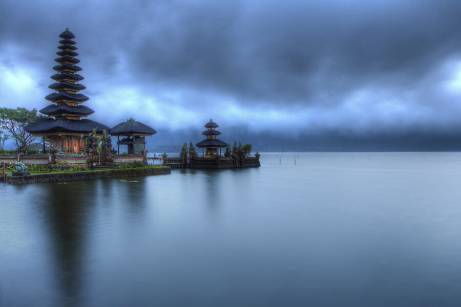 The temple mirrored on dark, still water under highland cloud — the early-morning look everyone comes for.