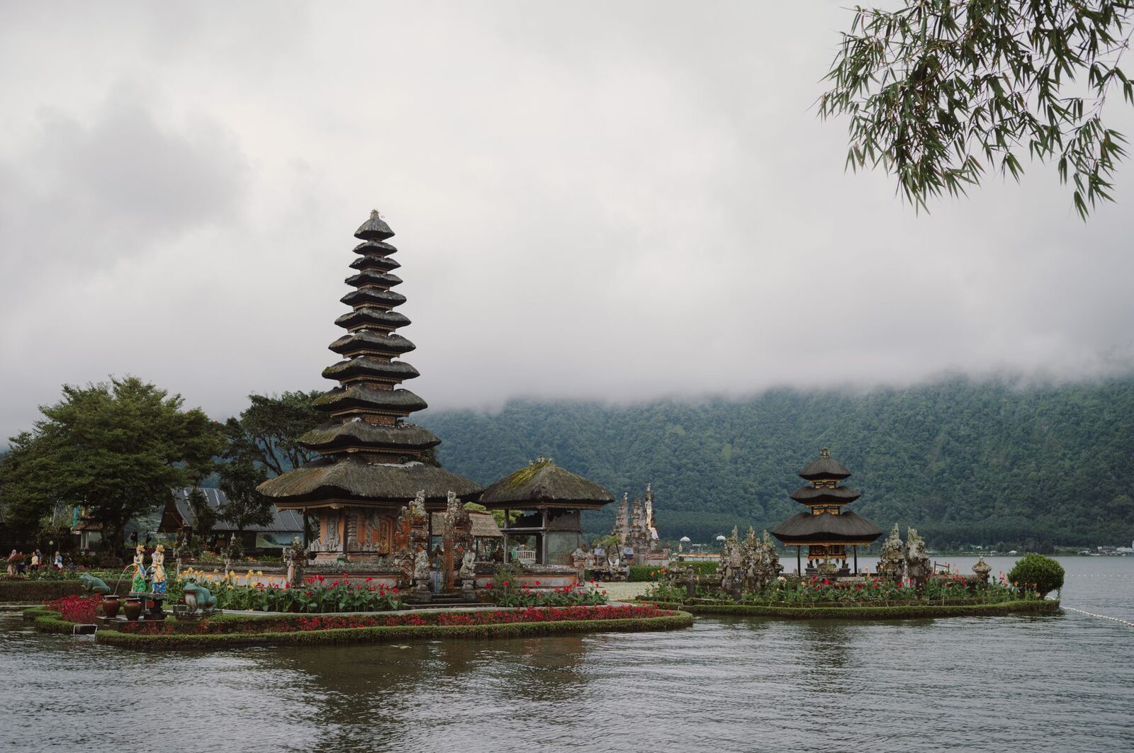 The shrines framed by an overhanging tree, the lake reaching back into the haze.
