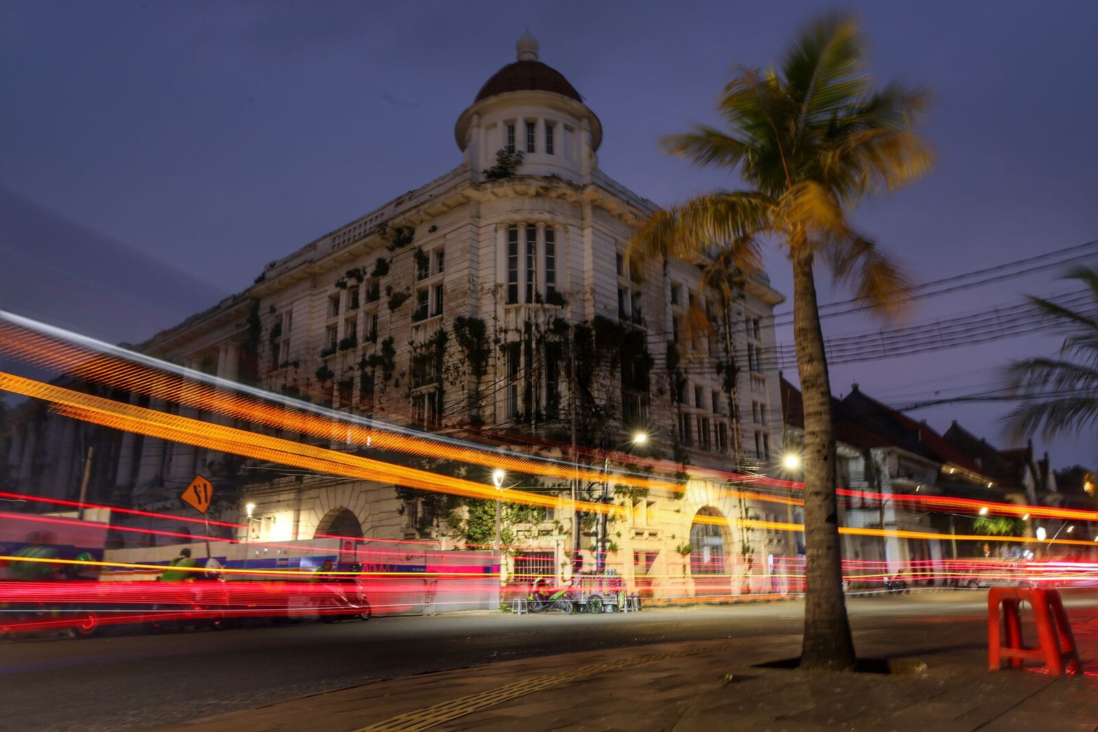 A south-Bali street after dark — warm light trails, bars waking up. The apps are busy in Canggu, Seminyak and the Bukit: a lot of travellers, nomads and expats, and some locals. Read profiles honestly, meet in public first, and keep your own ride home.