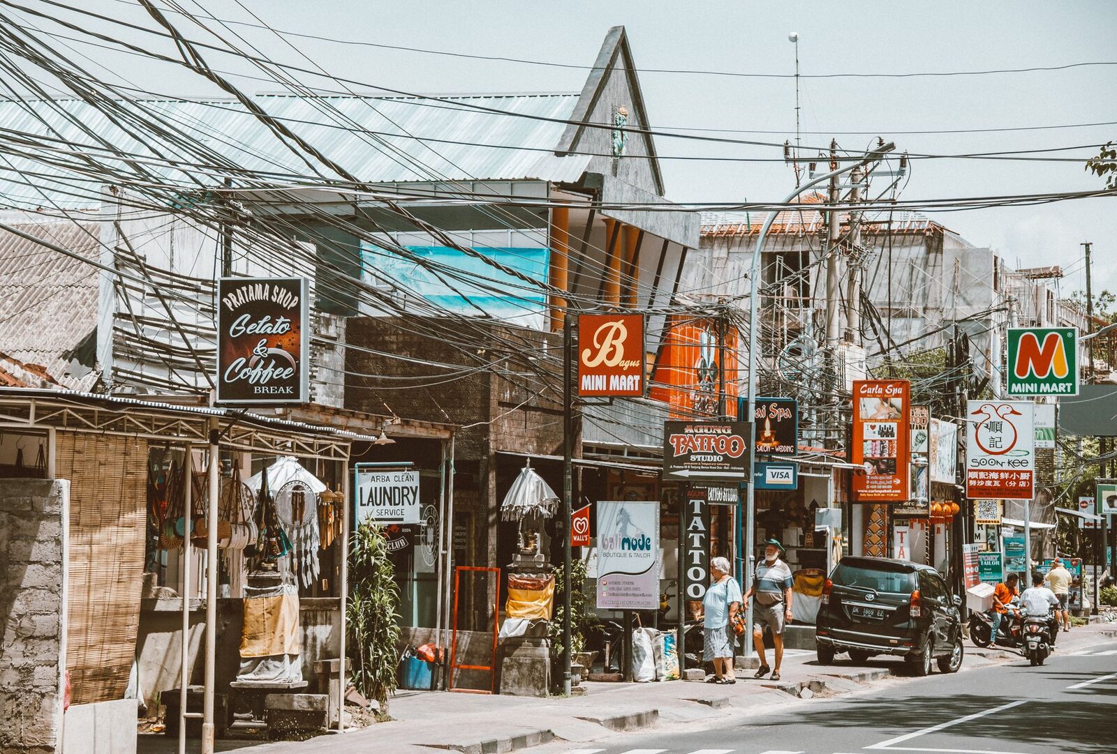Canggu's shop-lined main drag — cafes, signboards, tangled wires and scooters, the busiest of the four nomad bases.