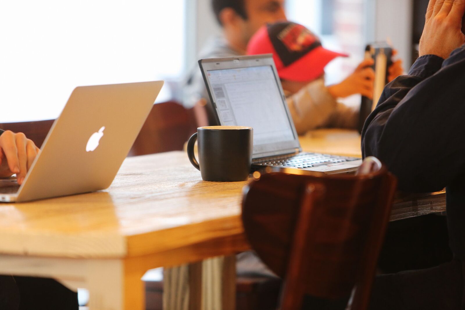 The classic setup — laptop, coffee and a shared wooden table.