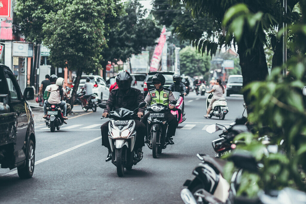 Cars and bikes sharing a narrow main road.