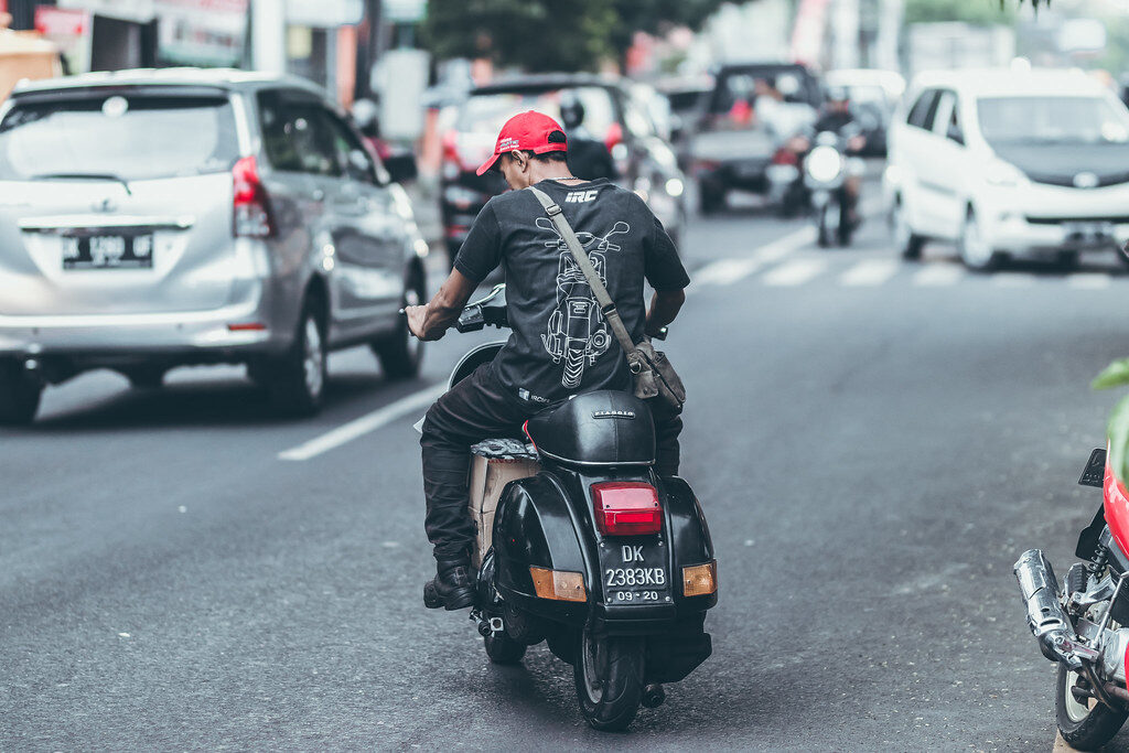 A rider threading between cars in slow-moving traffic.