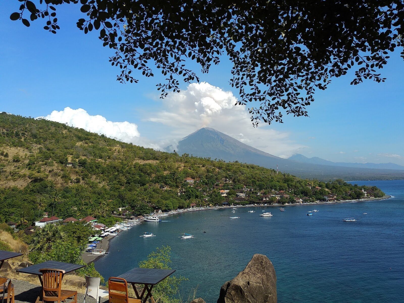 Amed's coast — a string of dark-sand bays with Mount Agung standing behind. Low-key and cheap, built around diving rather than sunbathing.