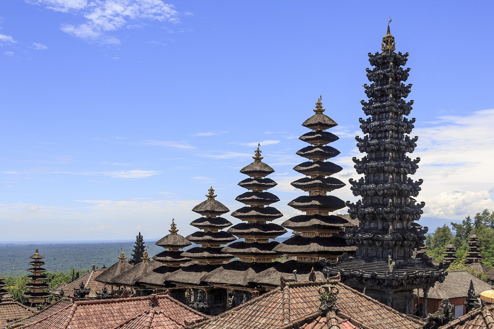 Tiers of black-thatched meru towers stacked up the hillside toward the sea.