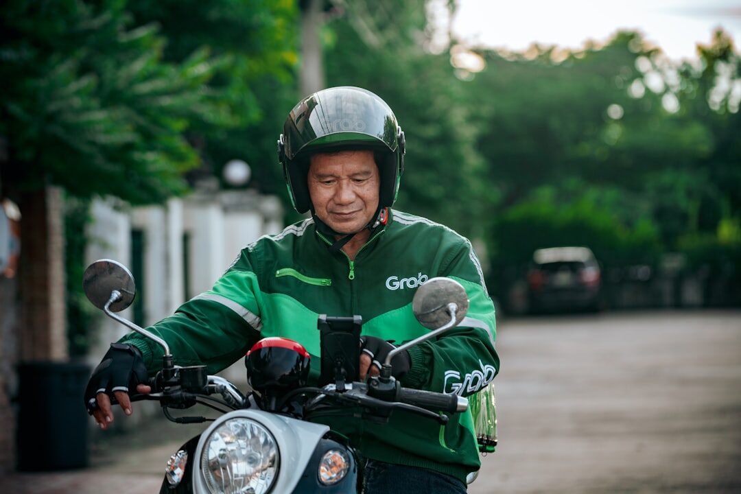 An app driver riding through town in his branded green helmet and jacket.