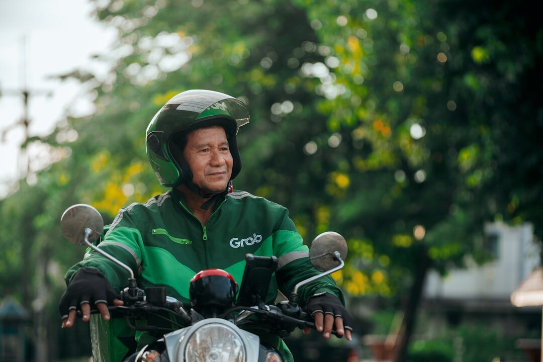 A ride-hailing driver in the green jacket and helmet — Grab and Gojek are the default for short hops, price shown up front before you book.