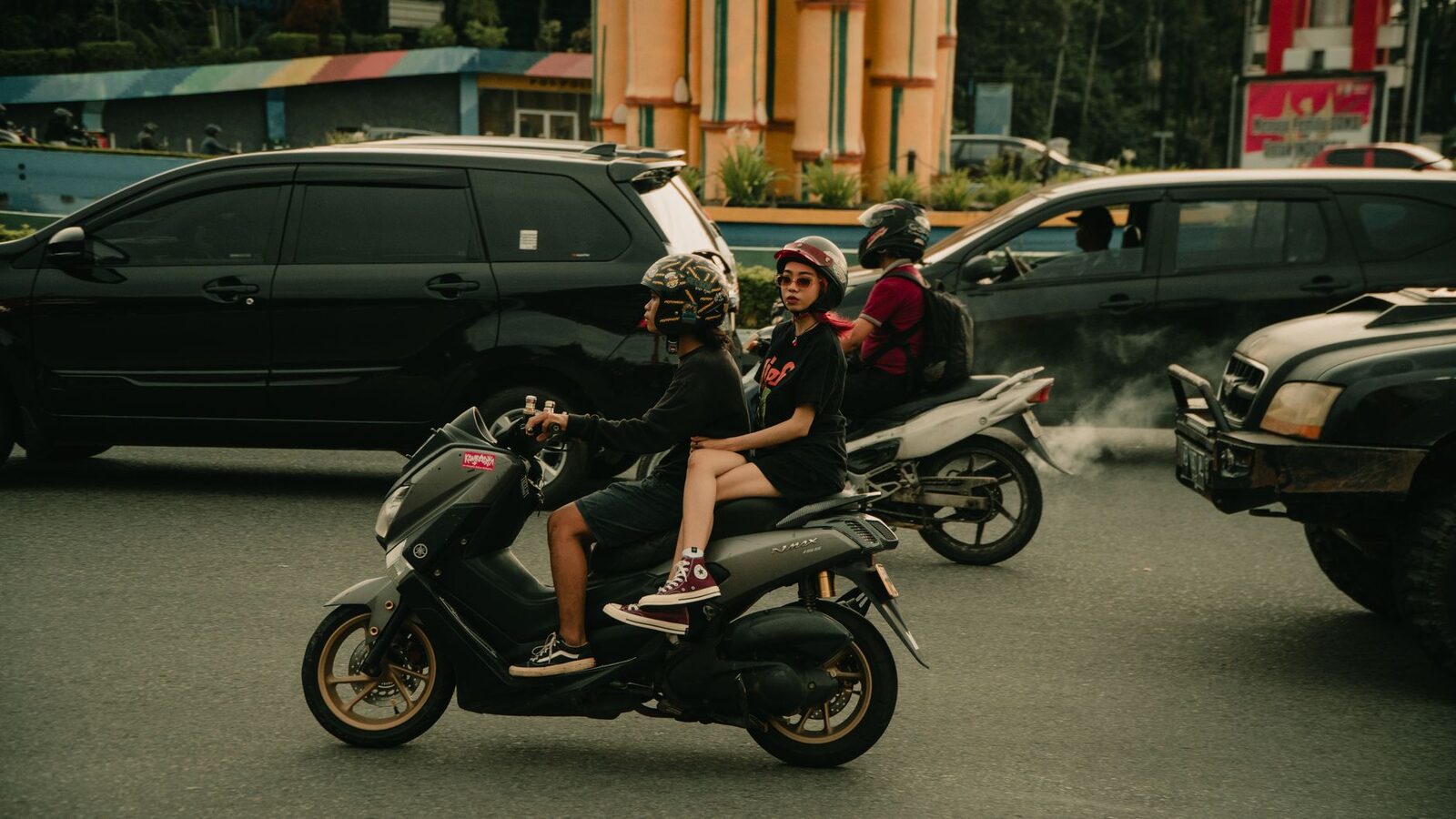 A scooter held up behind cars on a busy stretch.