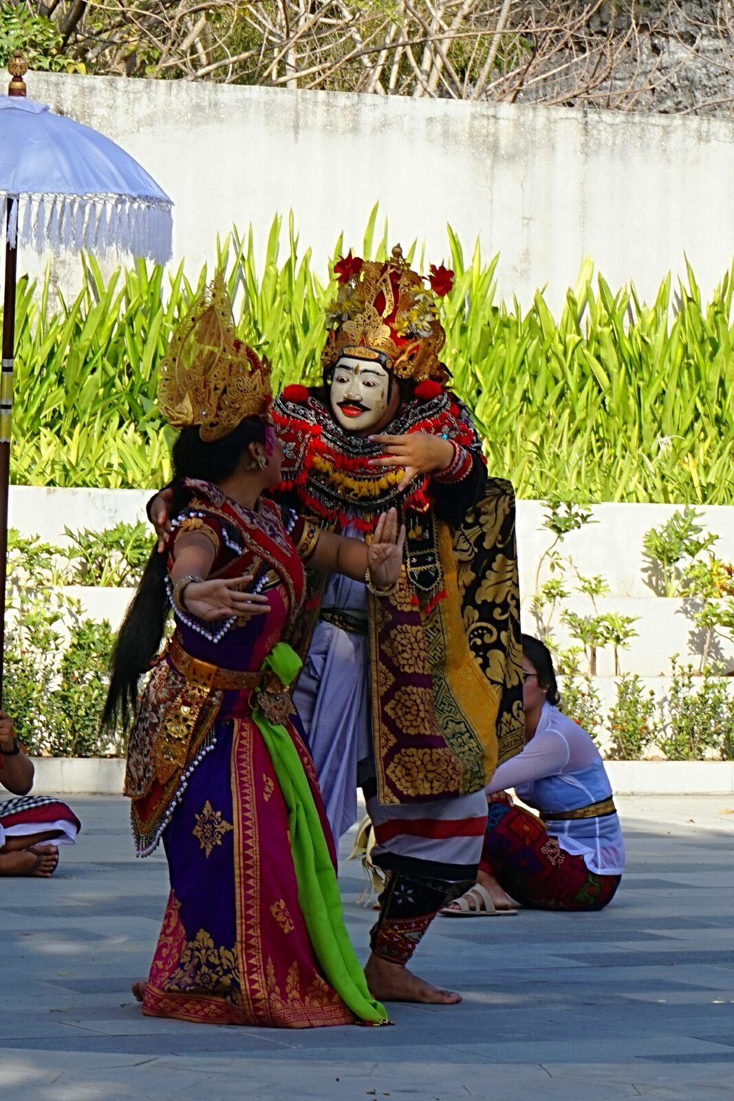 Barong and masked characters in full costume during a daytime performance.